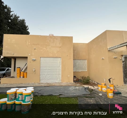 קירות חיצוניים צבועים עם דליי צבע וכלי עבודה בחצר
